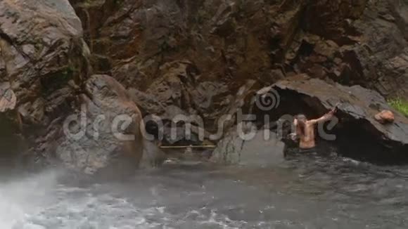 盖伊在瀑布处从岩石爬入河池视频的预览图