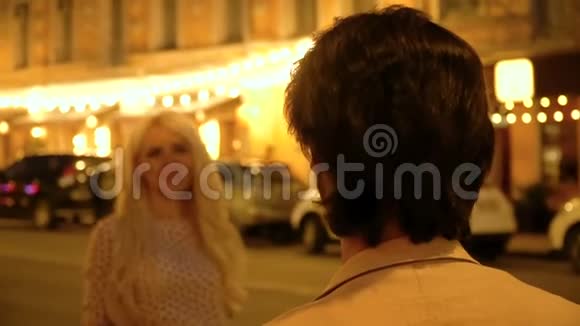 浪漫的情侣在夜晚城市的灯笼和橱窗展示的背景下拥抱和亲吻视频的预览图