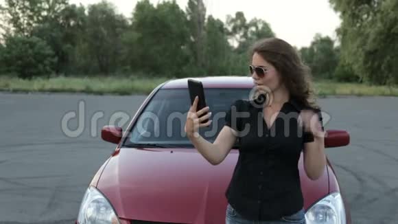 一个女孩在红色的汽车背景上用平板电脑拍照视频的预览图