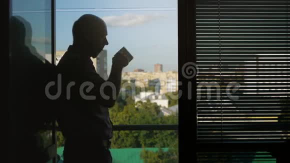 办公室里的人站在窗前喝酒视频的预览图