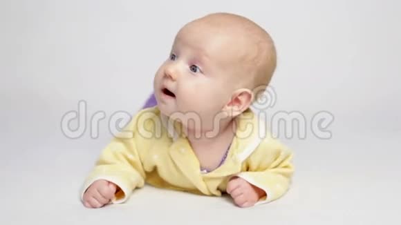 穿黄色衬衫的可爱宝宝躺在肚子上视频的预览图