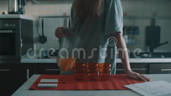笨手笨脚的黑发女人把橙汁倒进红色的玻璃杯里溅得到处都是视频的预览图