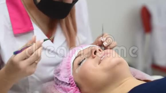 专业美容师进行睫毛延伸手术现代美容院的老板和客户视频的预览图