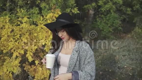 戴着黑帽子戴着眼镜在户外喝咖啡的年轻美女视频的预览图