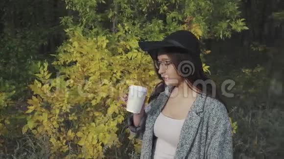 戴着黑帽子戴着眼镜在户外喝咖啡的年轻可爱女子视频的预览图