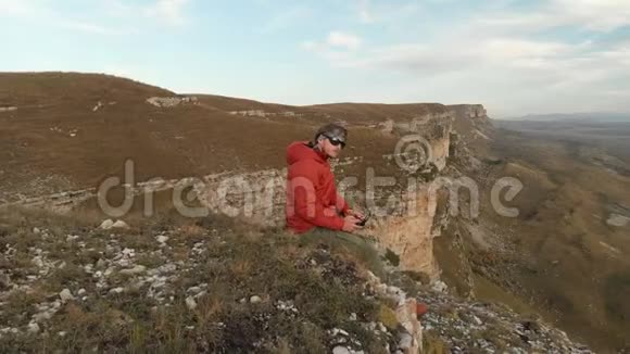 鸟瞰一只留着胡须的雄鸟它与一架无人机的遥控器沿着悬崖附近的高原边缘行走视频的预览图