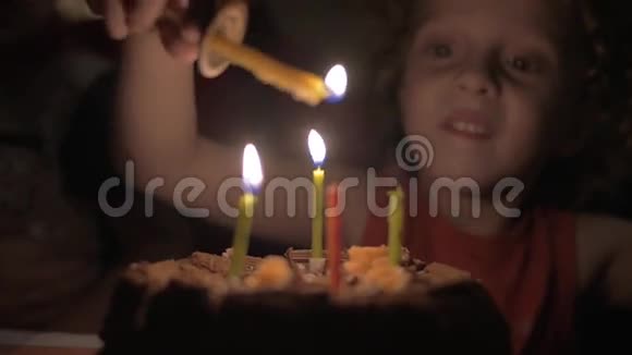 小女孩在黑暗中点燃生日蛋糕上的蜡烛的慢镜头视频的预览图