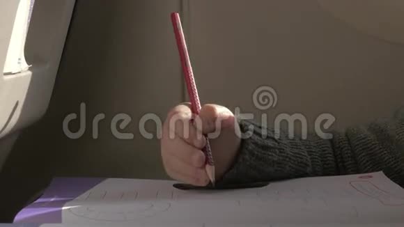 飞机上坐着一个小男孩用铅笔在纸上画画视频的预览图