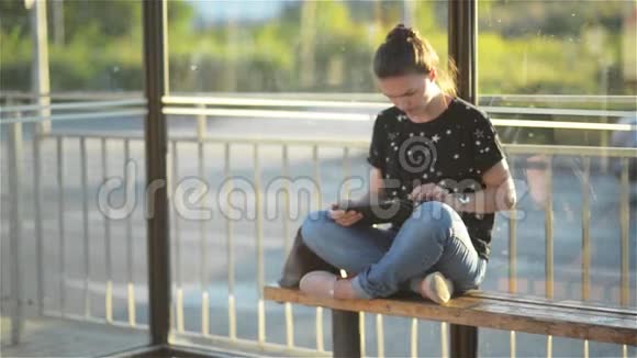 年轻女子在火车站等公共交通工具时看着她的平板电脑或电子书视频的预览图