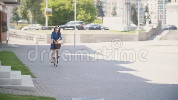 一个美丽的黑发女孩骑着自行车在繁忙的道路上行驶着汽车慢悠悠视频的预览图
