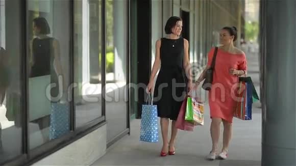 幸福的年轻女性用购物袋指着城市的橱窗销售消费主义和人的观念视频的预览图