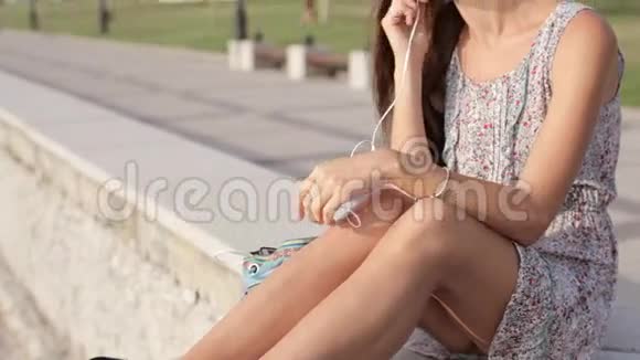 漂亮的年轻女子在海边穿着耳机视频的预览图