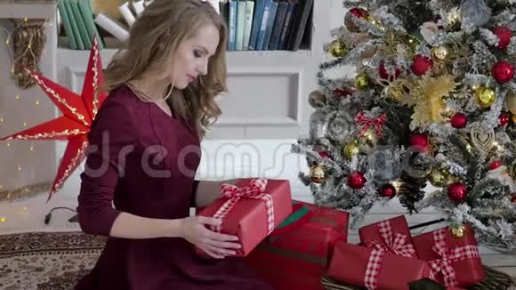 年轻女子坐在圣诞节室内的背景上带着礼物家庭圣诞网视频的预览图