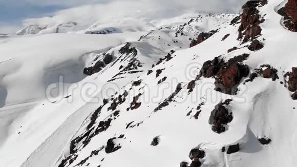 鸟瞰冬山景观埃尔布鲁斯南部度假胜地积雪覆盖的岩石斜坡视频的预览图