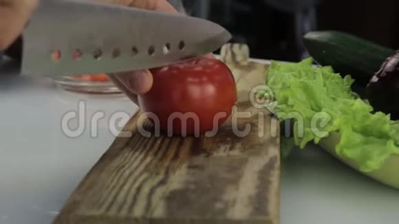 女人在厨房桌子上切番茄在木切割板上切蔬菜视频的预览图