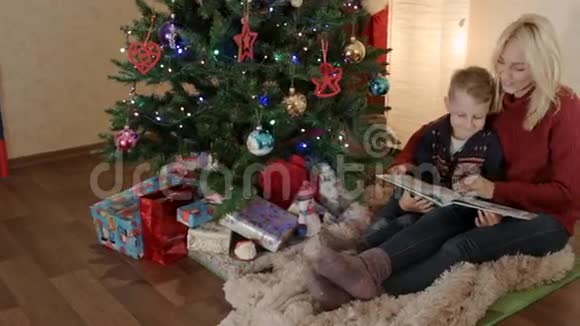 快乐的母子坐在圣诞树下翻着相册视频的预览图