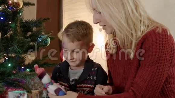 快乐的儿子和妈妈坐在新年树下玩雪人视频的预览图