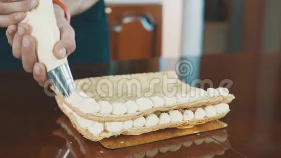 糕点厨师肌肉男挤压鞭打的奶油泡芙线上的蛋糕层视频的预览图