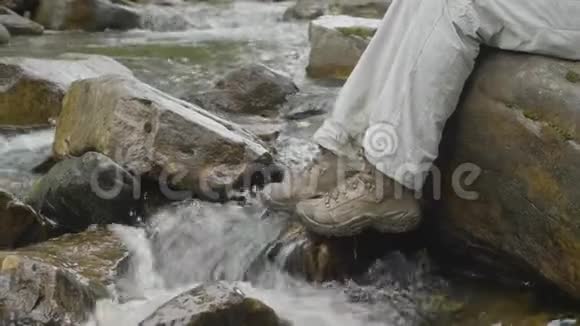 在岩石山脉上穿防水的徒步旅行靴高品质徒步旅行设备的概念视频的预览图