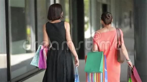 快乐的朋友带着购物袋在城里散步美丽的女人在购物成功后离开商场视频的预览图