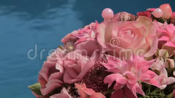 新娘花束躺在阳光甲板蓝色游泳池上视频的预览图
