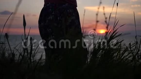 女孩穿着长裙站在沙滩上在风中成长欣赏着海上的日落高清1920x1080视频的预览图