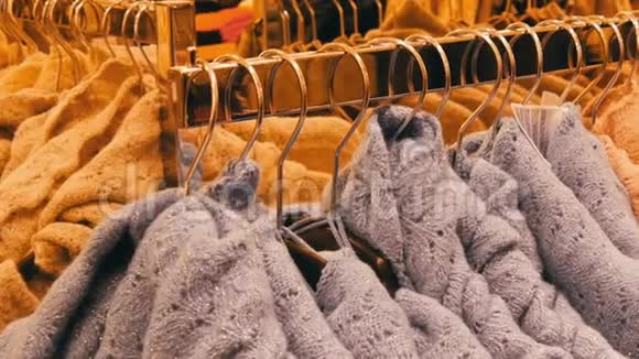 时尚的暖衣收藏挂在衣架上的各种颜色的新型温暖时尚毛衣数量众多视频的预览图