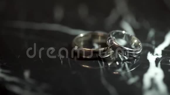 漂亮的结婚戒指反射在黑色光泽的背景上华丽的珠宝和闪光带着钻石的戒指视频的预览图
