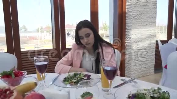 在餐桌旁的餐馆里男人给女孩一朵红玫瑰他们亲吻股票录像视频的预览图