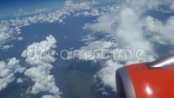 从飞机窗口到蓝天和白云的视野飞机机翼上的一个橙色涡轮机可以看到视频的预览图