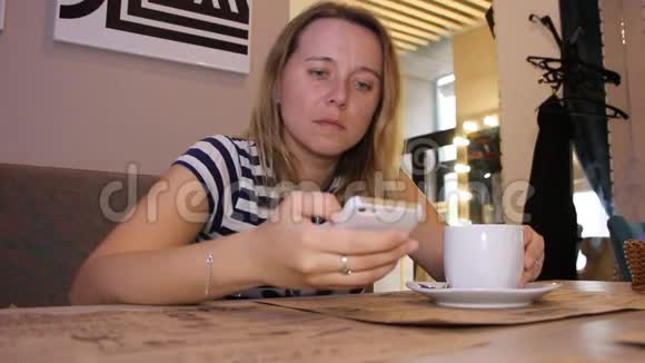 一个女人正在咖啡馆里用电话和一杯咖啡视频的预览图