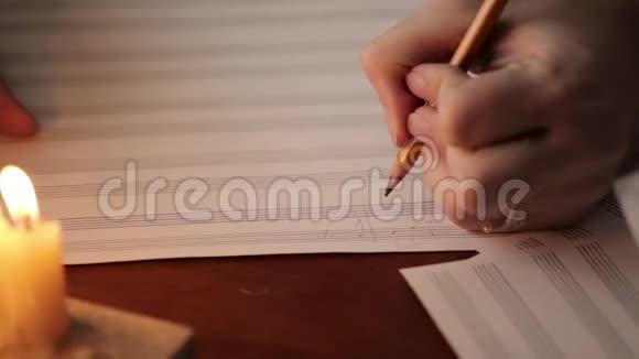 学生写音乐音乐家用铅笔在带有烛光的音乐书中作曲音乐家的特写视频的预览图