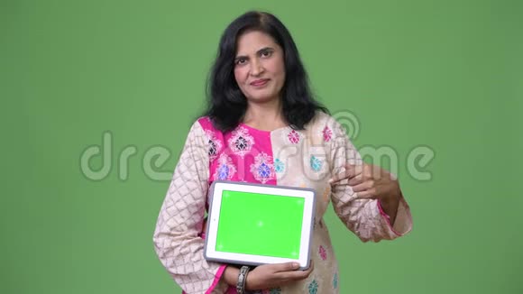 成熟美丽的印度女人展示数字平板电脑和手指视频的预览图