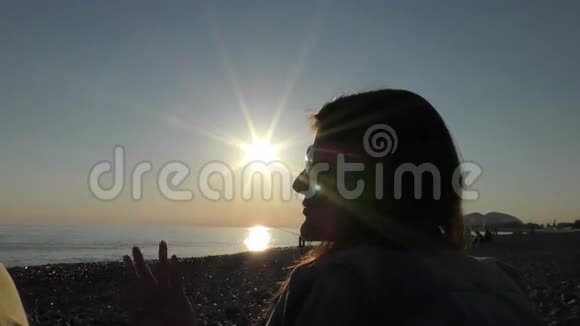 日落时分海滩上一个年轻迷人的女人在谈论一些事情视频的预览图