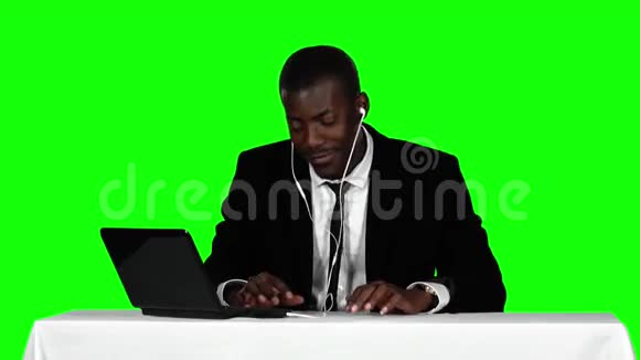 商人坐在书桌前听耳机里的音乐绿色屏幕视频的预览图