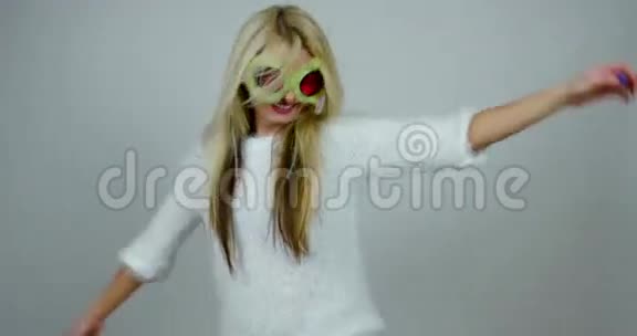 一个快乐的女孩戴着有趣的红色眼镜和绿色的毛皮跳舞的肖像视频的预览图