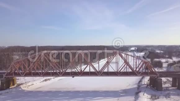 铁路悬索桥供火车穿越冬季河航空观冬季火车桥穿过冰冻的河流视频的预览图