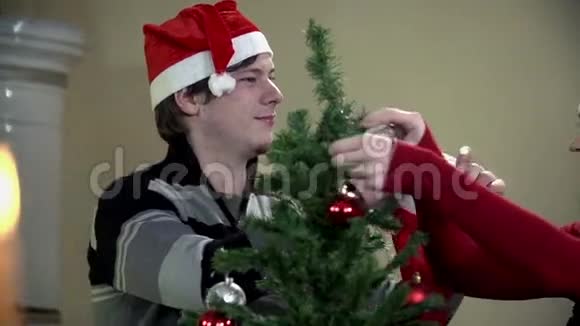 在装饰圣诞树的时候把圣诞老人的帽子戴在女孩头上视频的预览图