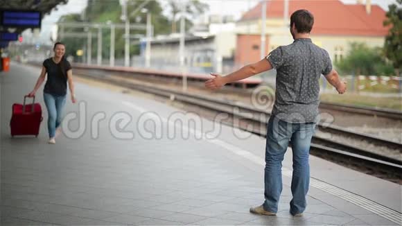年轻夫妇很高兴在火车站再次见面女孩跑去见她的男朋友扔了一个手提箱视频的预览图