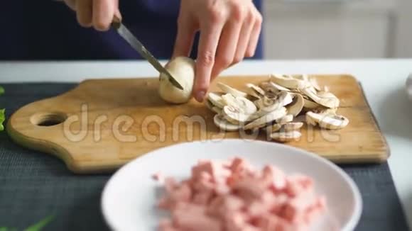 在家里的厨房里用女孩的双手在木板上切蘑菇做披萨视频的预览图