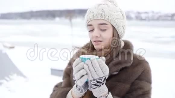 可爱的小女孩在冬天在室外喝热咖啡视频的预览图