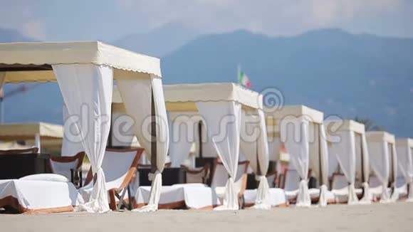 在黄昏的灯光下一片绿松石海前的木制日光浴床在著名的意大利沙滩上的日光浴视频的预览图
