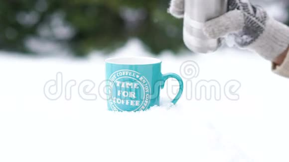戴手套的手在雪地上从保温瓶往杯子里倒热茶的特写镜头慢慢地视频的预览图