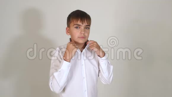 一个穿白色衬衫的小男孩在工作室的白色背景上的肖像视频的预览图