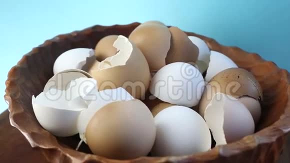 在蓝色背景上旋转碎蛋壳的木碗视频的预览图