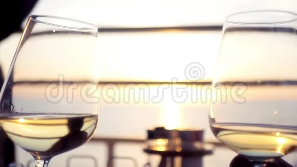 两个美丽的酒杯与葡萄酒在日落背景在海上高清1920x1080慢动作视频的预览图