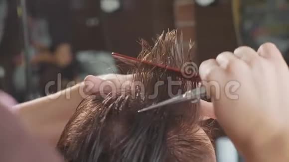 理发店里理发师的特写用剪刀缓慢地剪头发视频的预览图