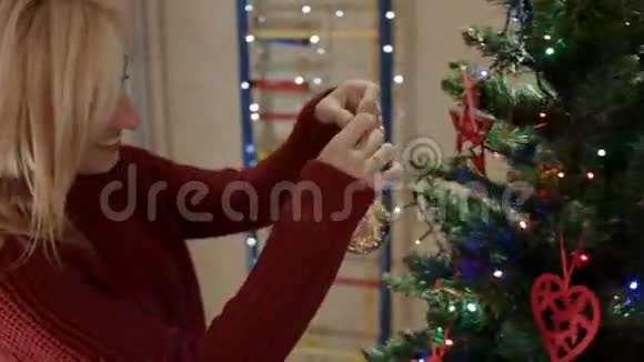 妈妈在圣诞树树枝上挂着老式的新年树玩具视频的预览图