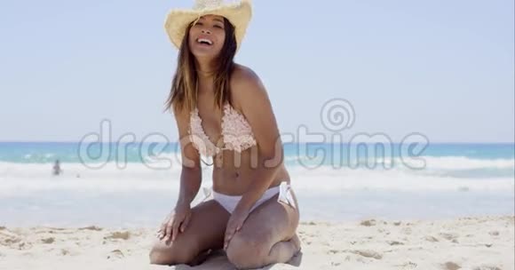 快乐的年轻女子跪在沙滩上视频的预览图