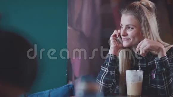 年轻漂亮的女孩喝咖啡用智能手机聊天视频的预览图